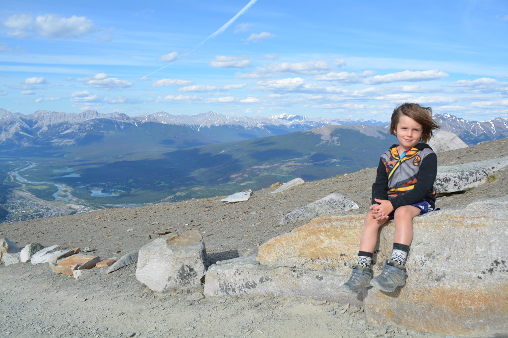 One of the Royal boys sitting on a rock on a trail