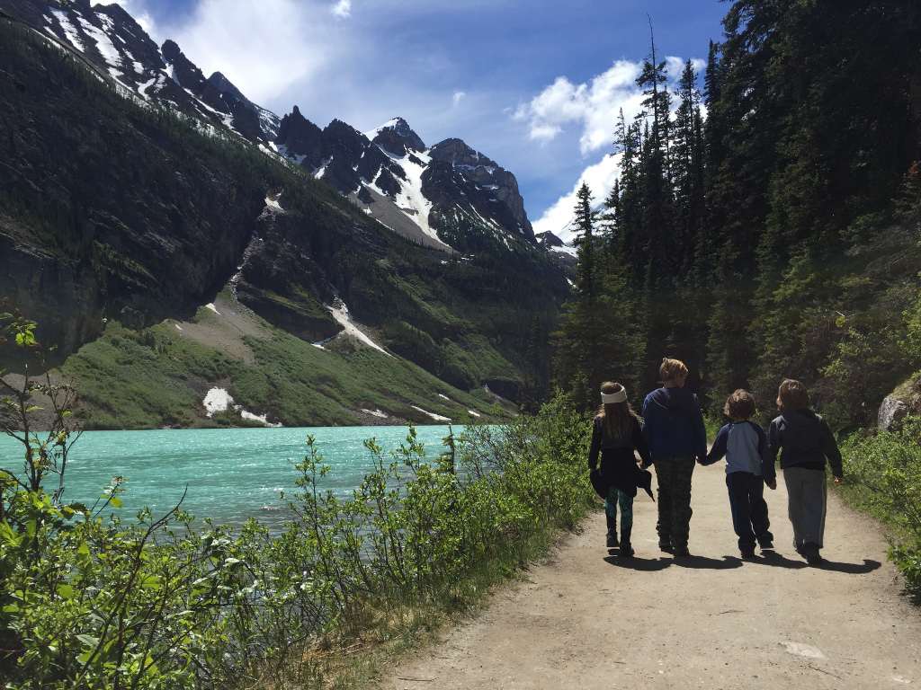 Royal kids walking near body of water and mountains