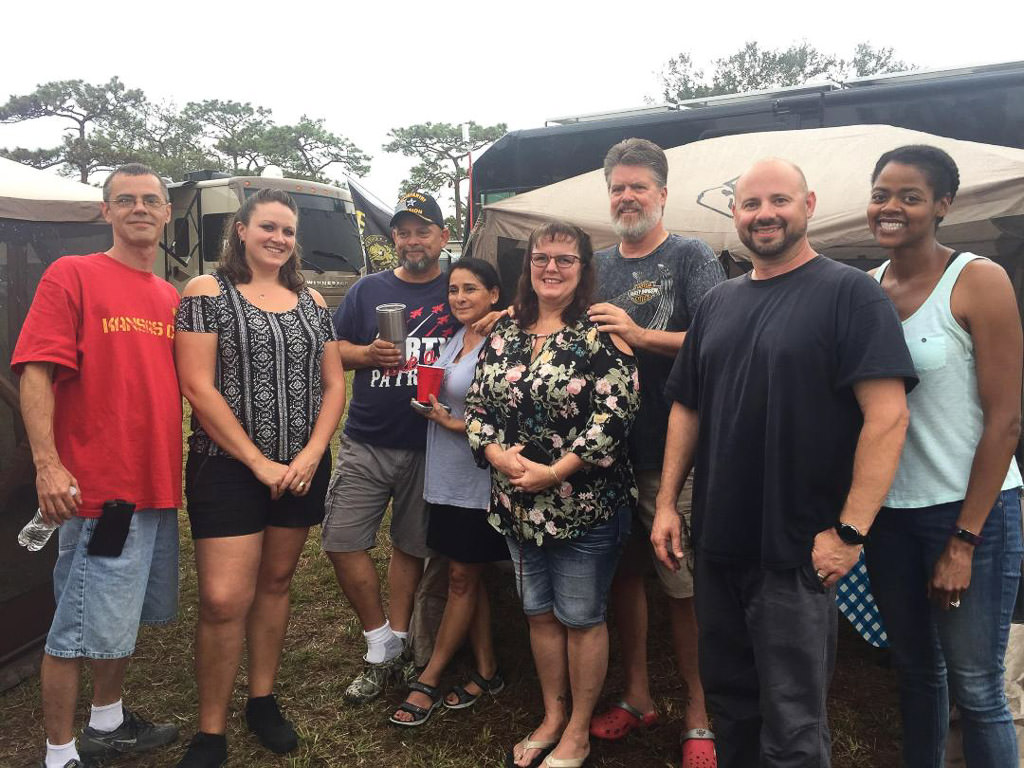 Sabrina and Kenny standing with six friends in front of motorhomes