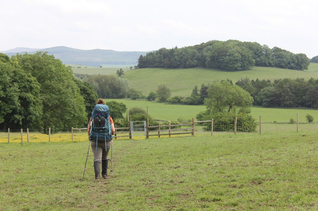 Woman hiking across a grassy field.