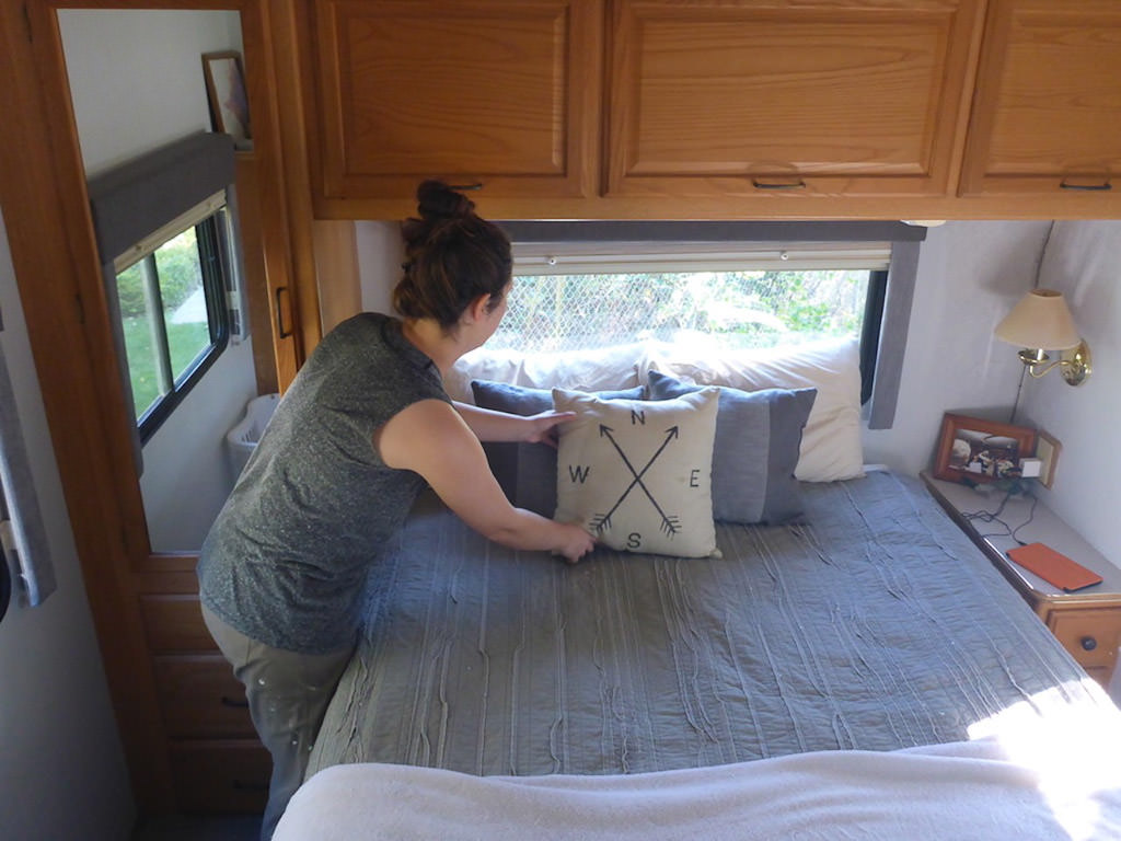 Woman putting a decorative pillow on bed.