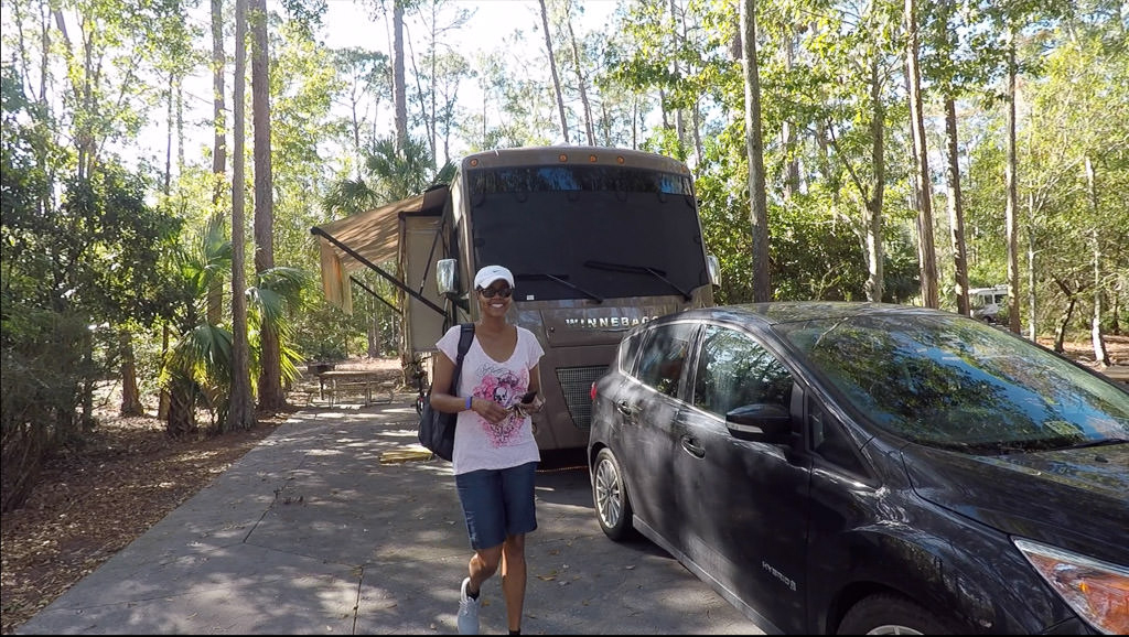 Sabrina walking down road next to RV and car