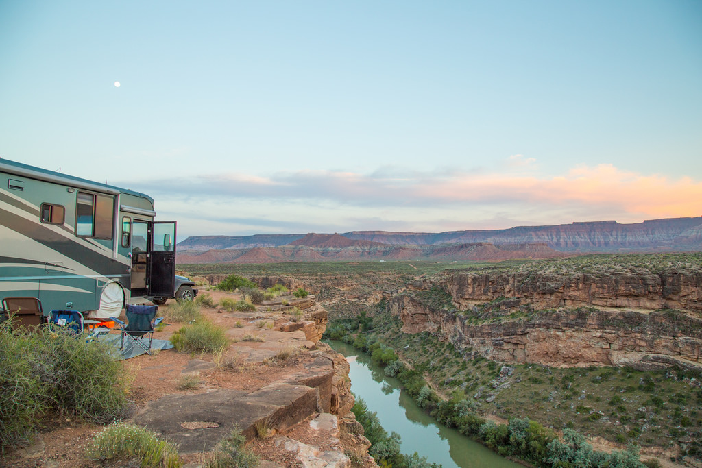 Winnebago Journey with camp chairs out front parked next to river and mountains across the river