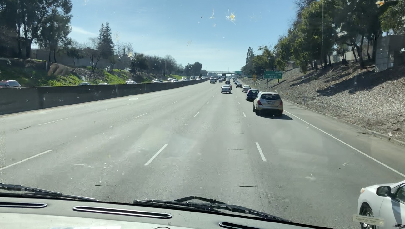 View out of windshield of traffic driving down road 