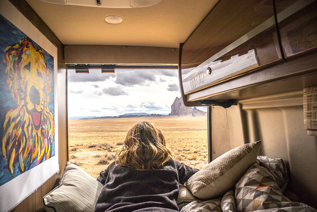 Katherine laying on bed looking out back of Travato with the doors open