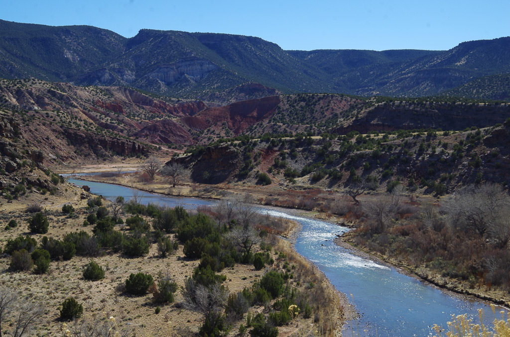 River running through desert landscape and high rocky hills.