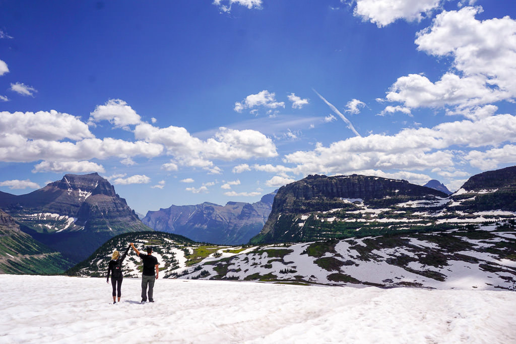Lindsay and Dan holding hands in the air looking out over the mountains 