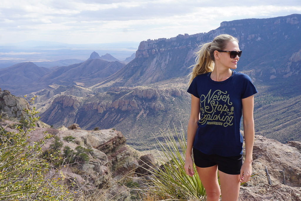 Lindsay standing on cliff side with mountains behind her