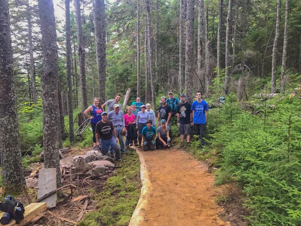 Group of volunteers posing on a trail between trees