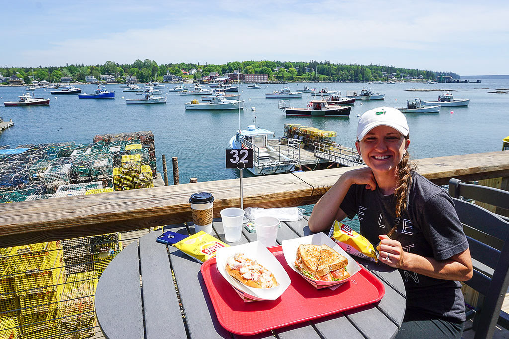 Brittany eating at table outside by water