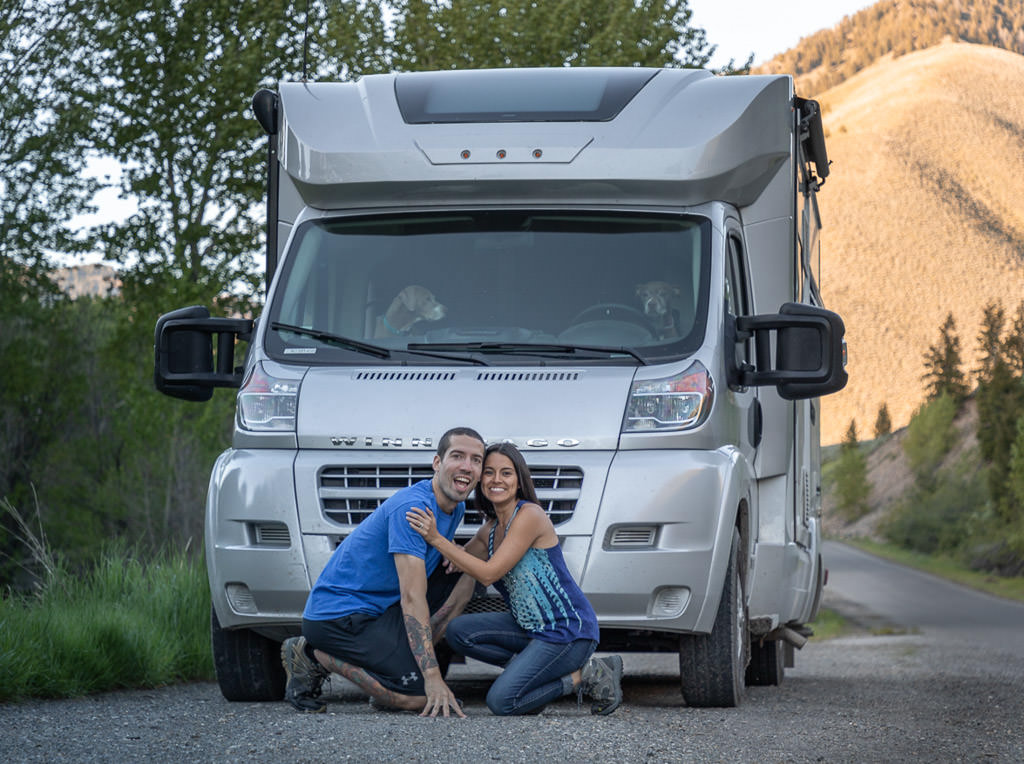Jon and Nadia kneeling in front of their parked Winnebago Trend