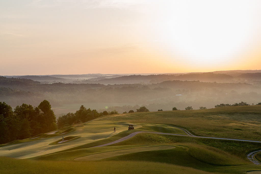 Golfers on green with forest and sunrise 