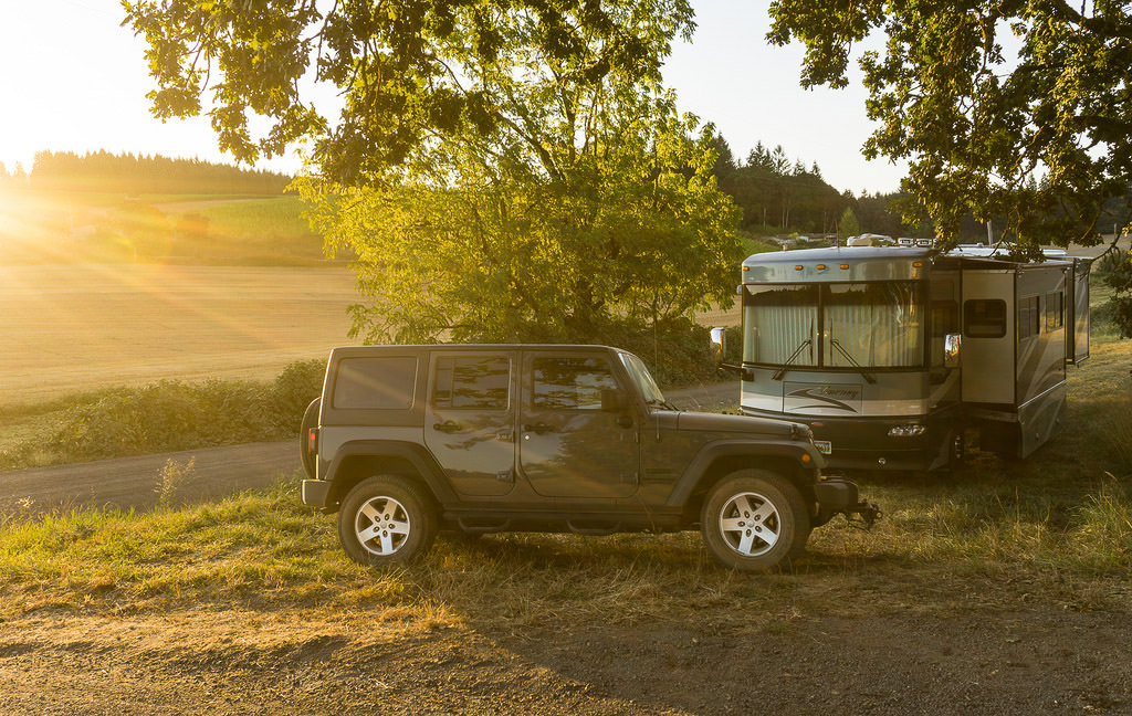 Winnebago Journey and tow car parked in grass field