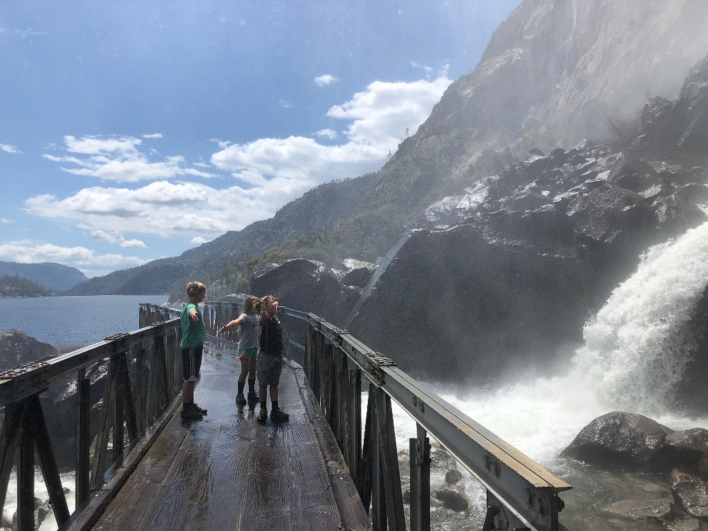 Kids standing on a bridge beneath a waterfall
