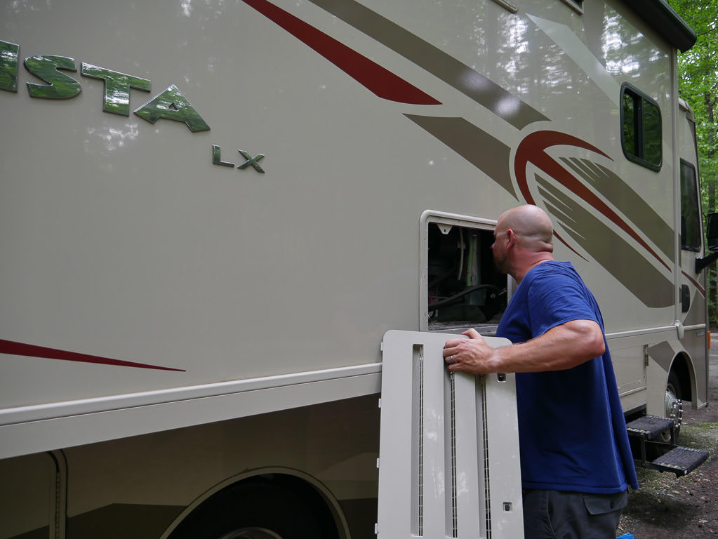 Kenny holding vent cover to fridge while inspecting for bugs and nests