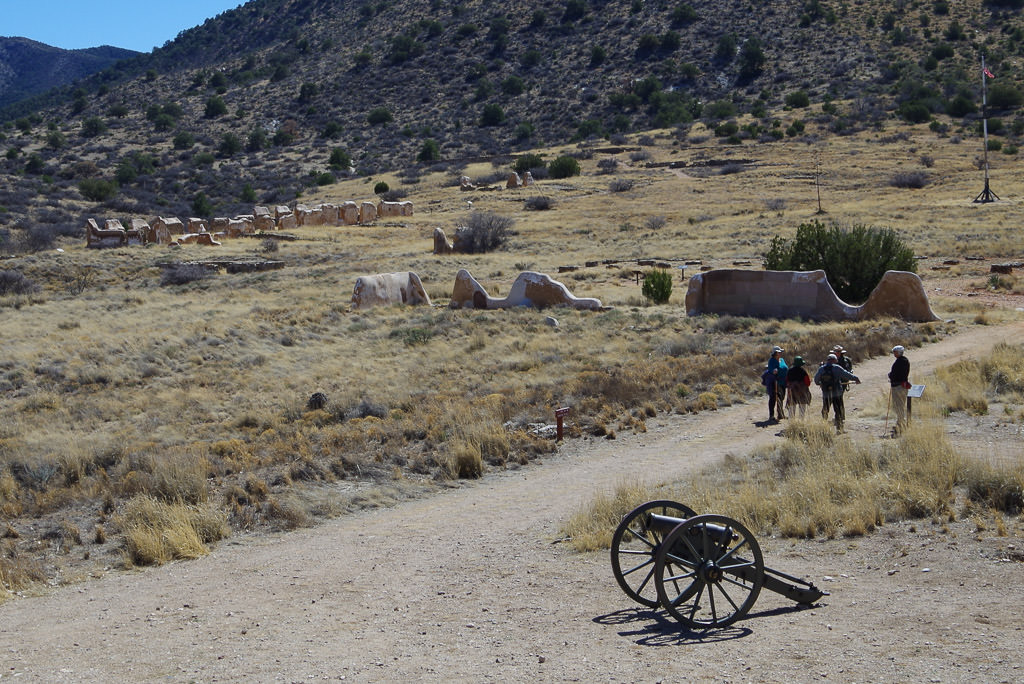 Group standing on path at Fort Bowie with ruins spread across the dry landscape.