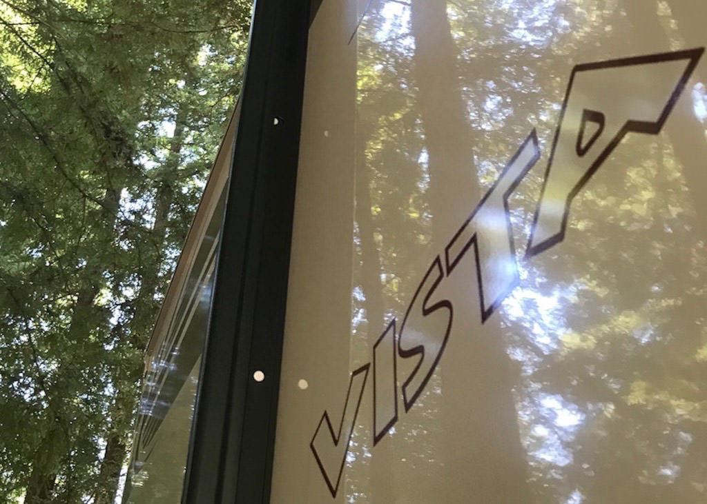 Winnebago Vista underneath towering trees. 