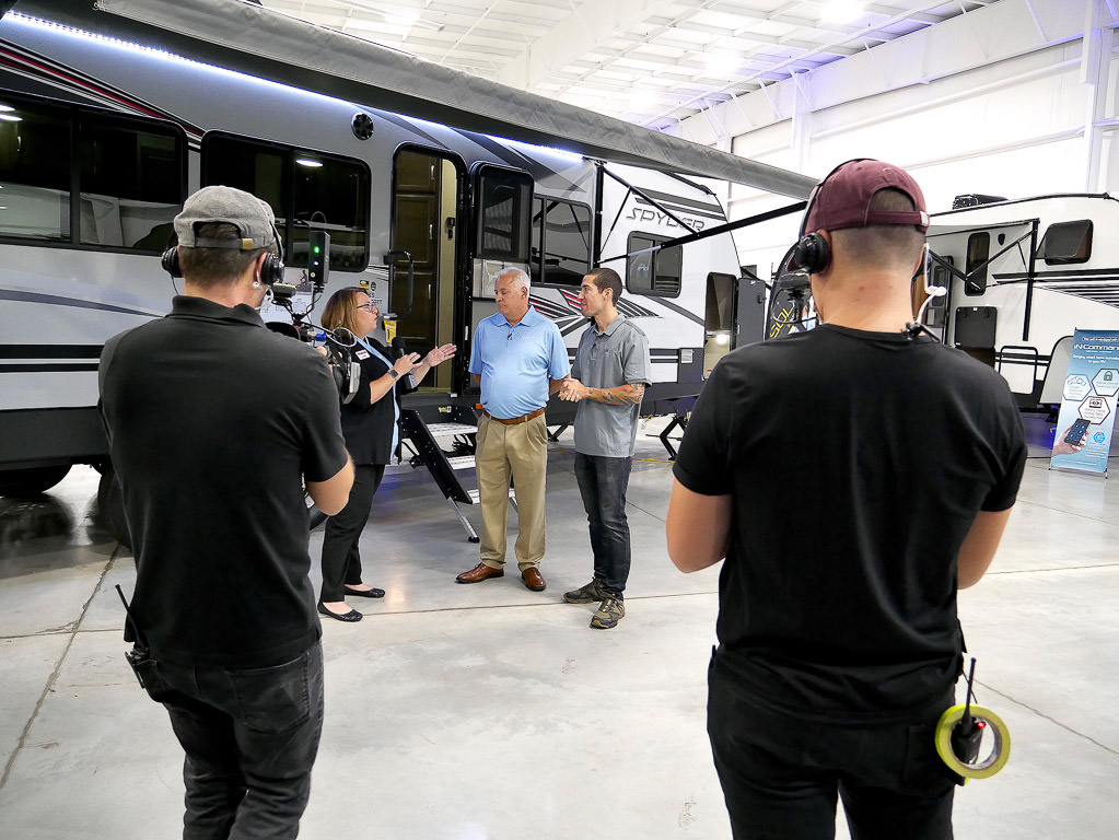 Camera crew filming group outside Winnebago Spyder.