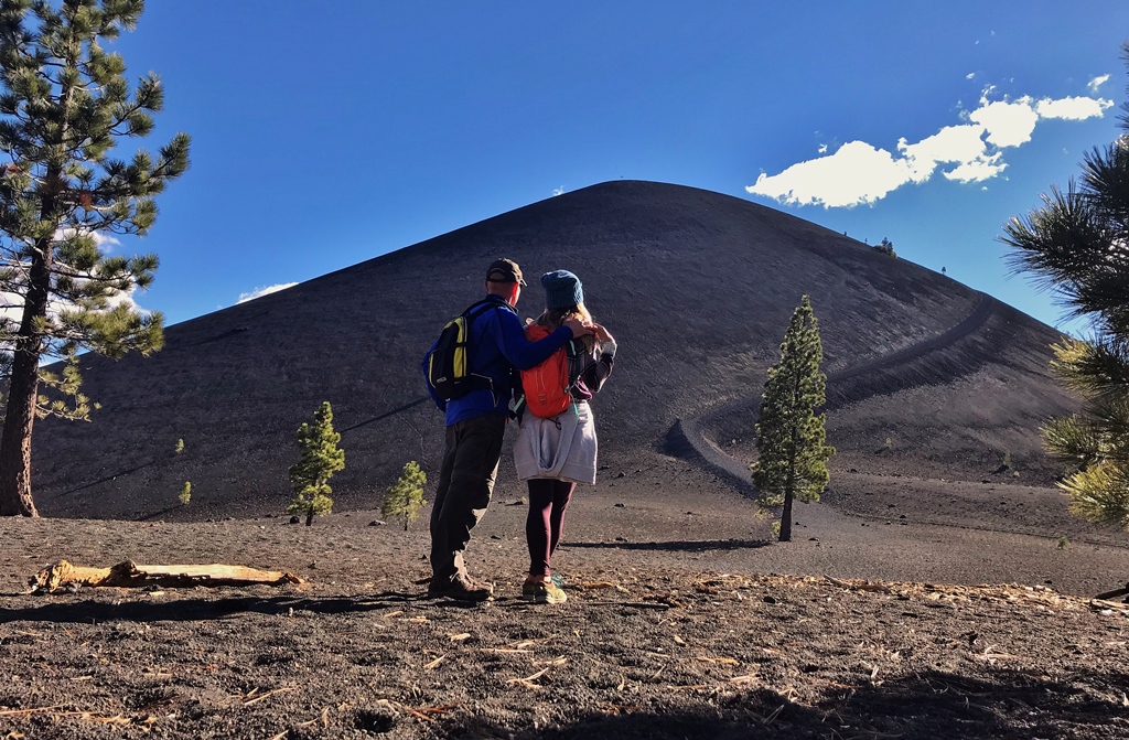 James and Stef standing with backs towards camera in front of a volcano