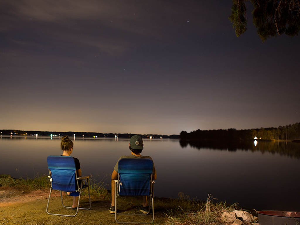 Brittany and Jordan sitting in camp chairs next to the water