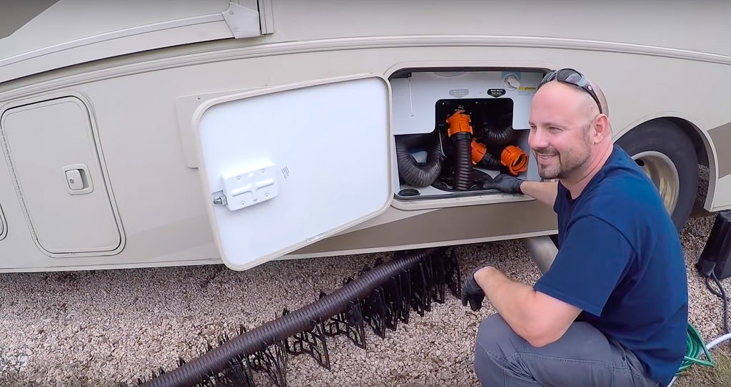 Kenny wearing gloves and kneeling down next to sewer bay