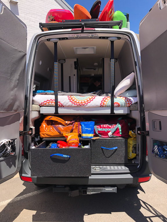 Back end of a Winnebago Revel with the doors open showing the extensive storage space.