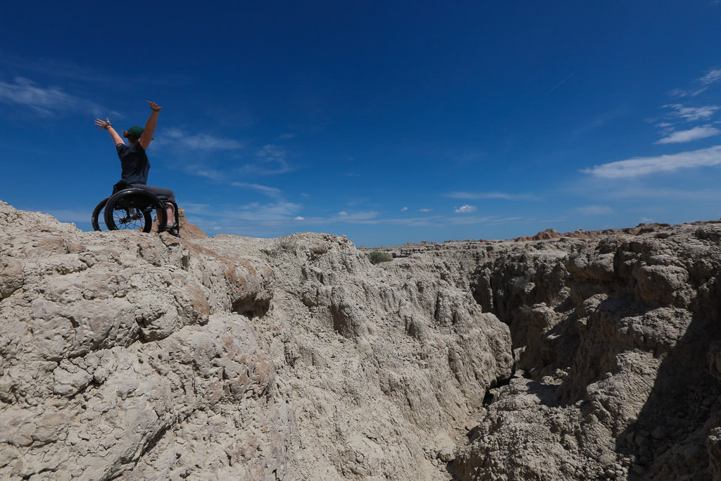 Nerissa with arms in the arm at the edge of a rocky cliff. 
