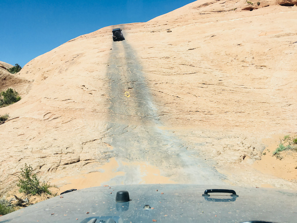 Jeep driving up side of a steep rocky hillside.