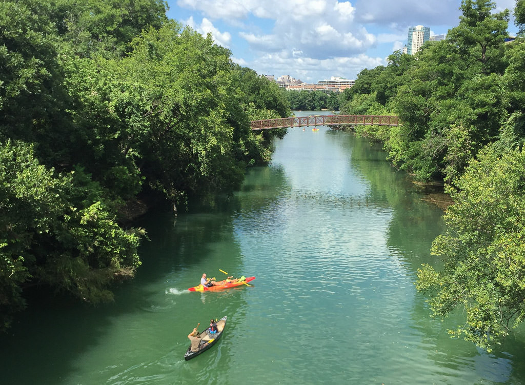 People in kayak and canoe going down Lady Bird Lake.