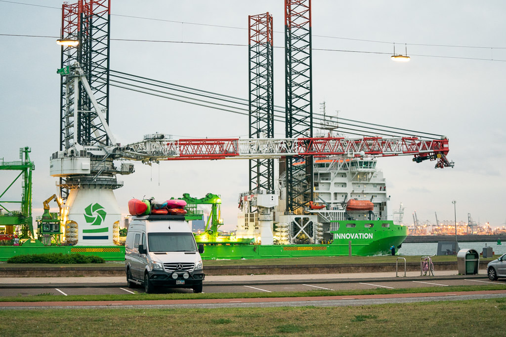 Winnebago Revel parked in parking lot with large ferry in background.