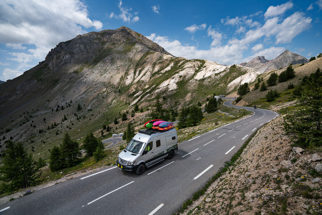 Winnebago Revel driving on paved road with mountains behind.