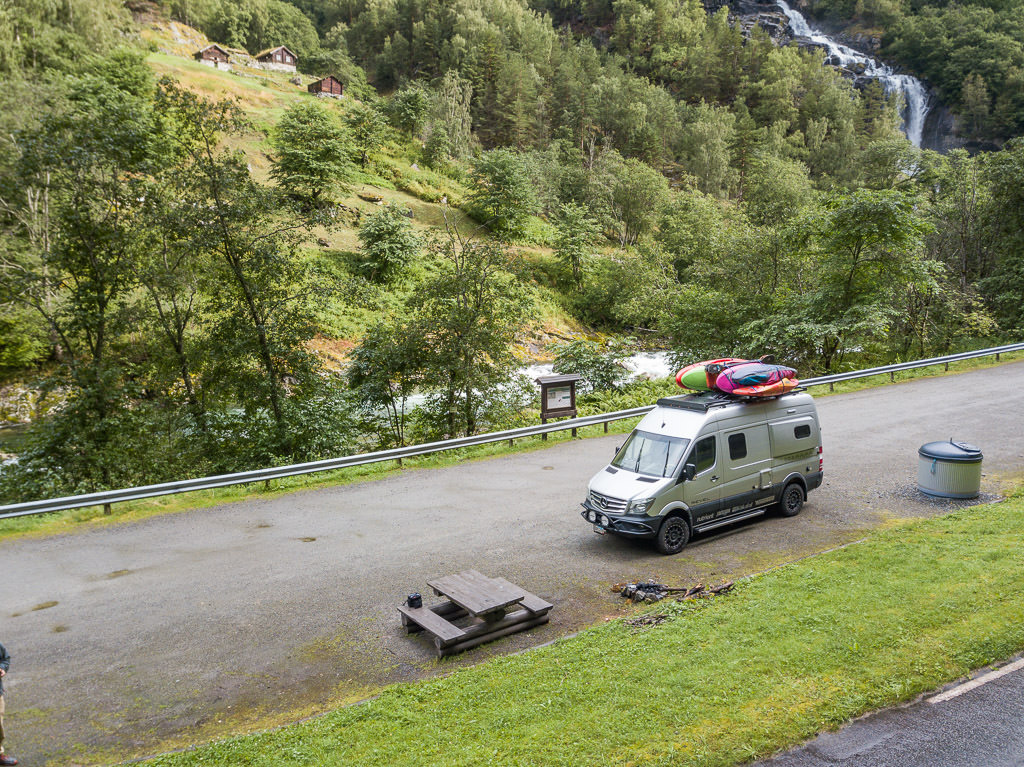 Winnebago Revel parked at hillside campsite with picnic table out front. 